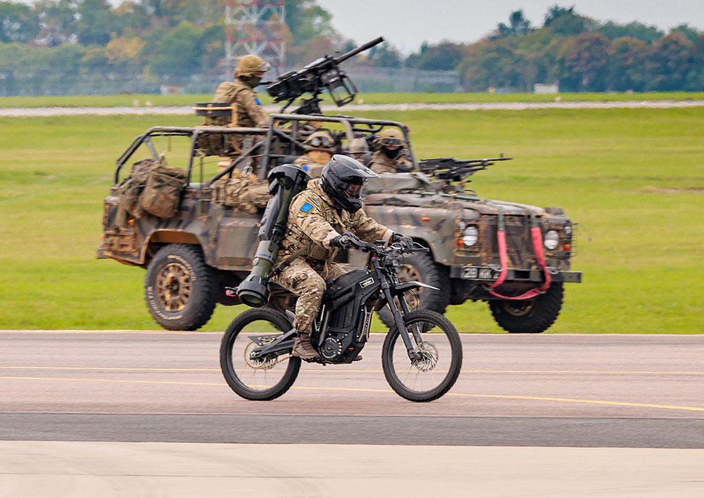 Elements of 2nd Battalion, Parachute Regiment, having disembarked the Atlas (A400M), race along the airfield manoeuvring area. Image shows an assault Landrover containing troops and an electric bike with rider.